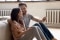 Un couple heureux est assis devant un système de chauffage et tient un smartphone.